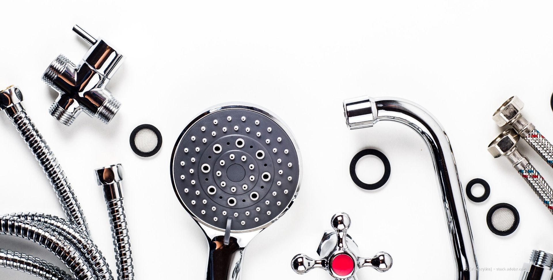 Klempner mit weißem Hut arbeitet an Rohren in einem Schrank.