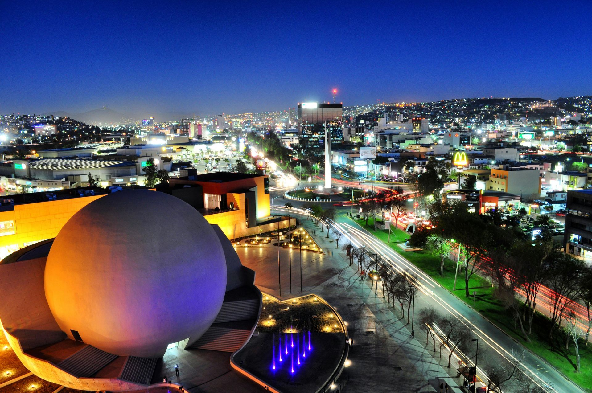 Night view of Tijuana, Mexico, cityscape with a large spherical building in the foreground, illuminated lights.