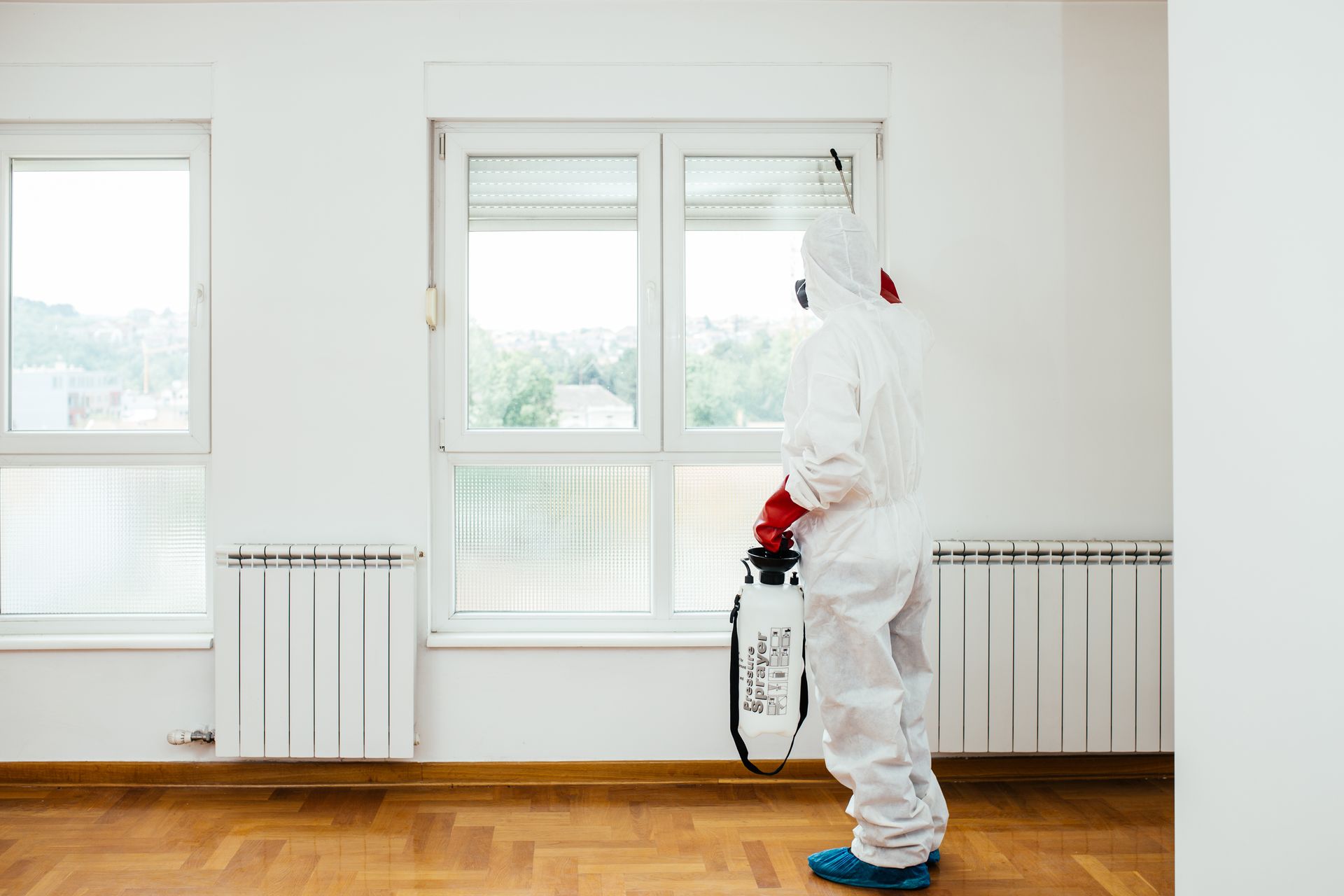 Exterminateur en tenue de travail pulvérisant un pesticide ou un insecticide