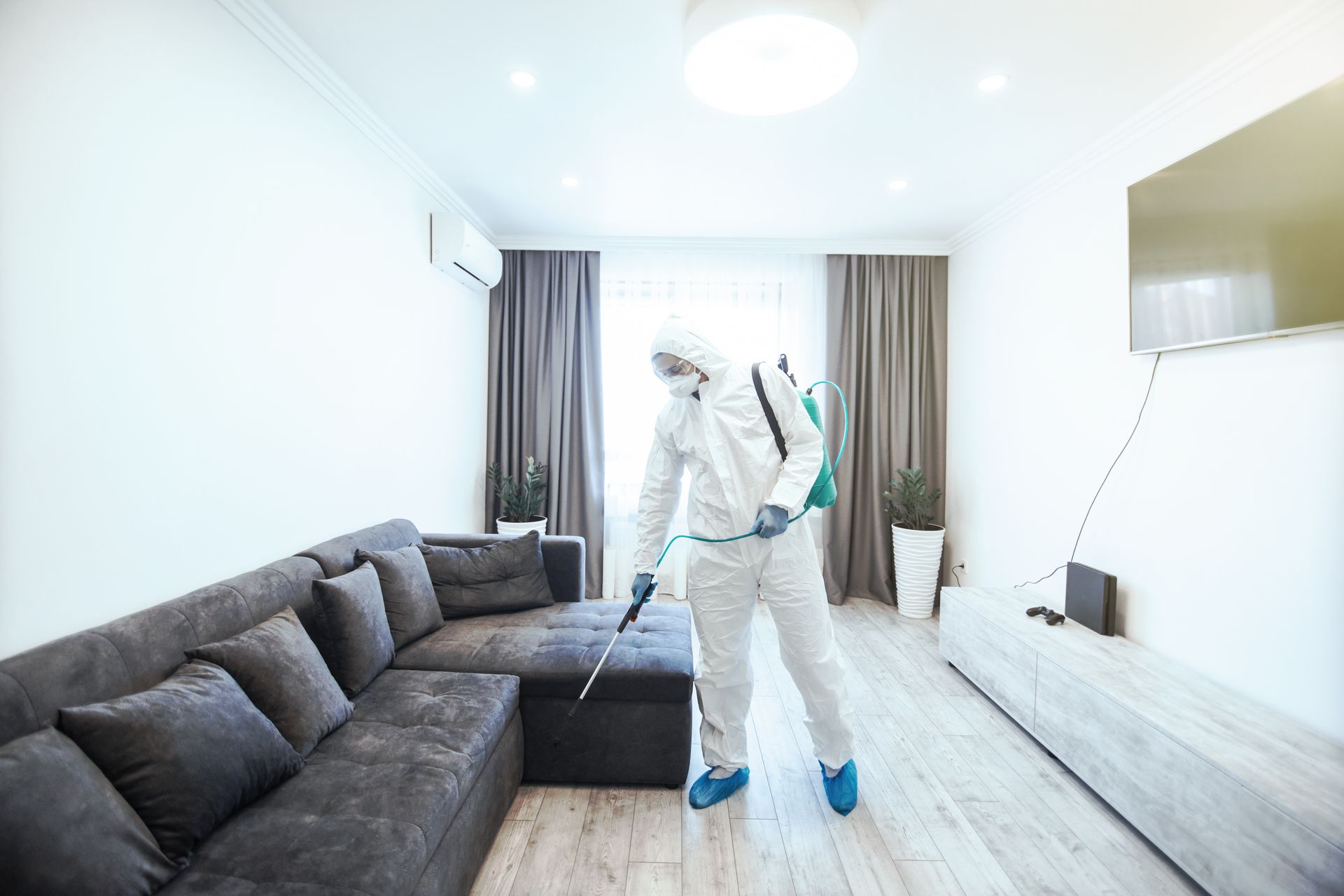 Un homme en tenue de protection désinfecte une zone contaminée dans une maison