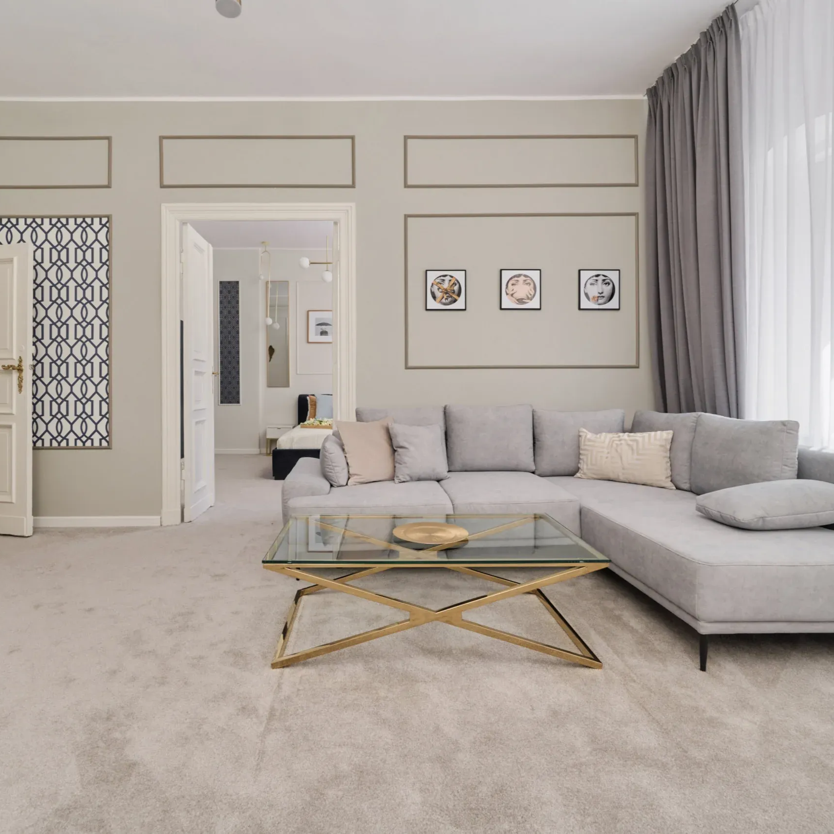 Living room with gray sectional sofa, gold coffee table, and neutral walls.