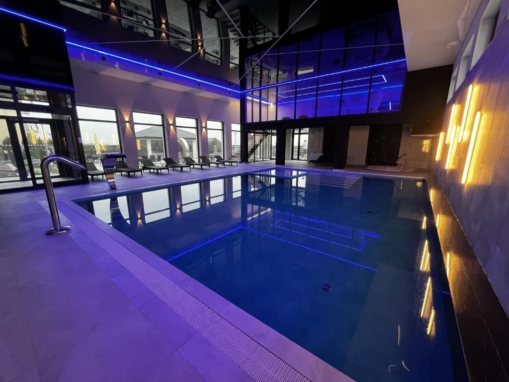Kryty basen z niebieskim oświetleniem, nowoczesną architekturą i szklanymi oknami.
