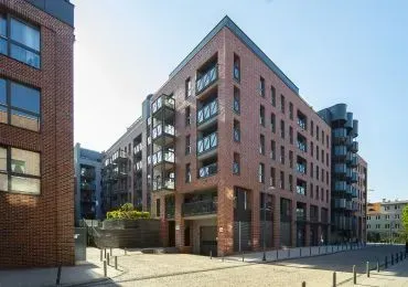 Duży ceglany budynek z wieloma oknami znajduje się w mieście.