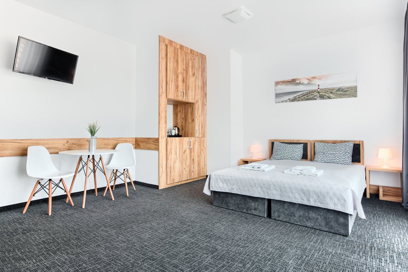 Nowoczesny pokój hotelowy z łóżkiem, stołem, krzesłami i drewnianymi elementami ściennymi.