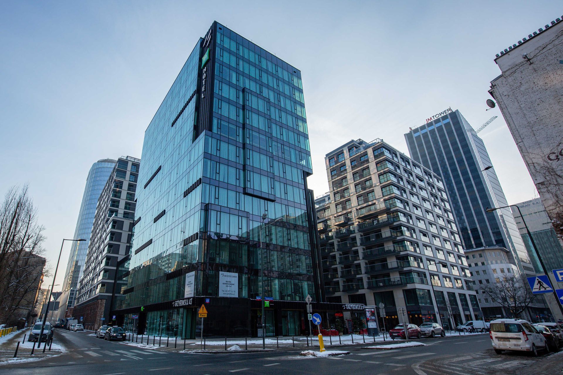 Nowoczesne szklane i stalowe budynki Mennica Residence biurowe na miejskiej ulicy.