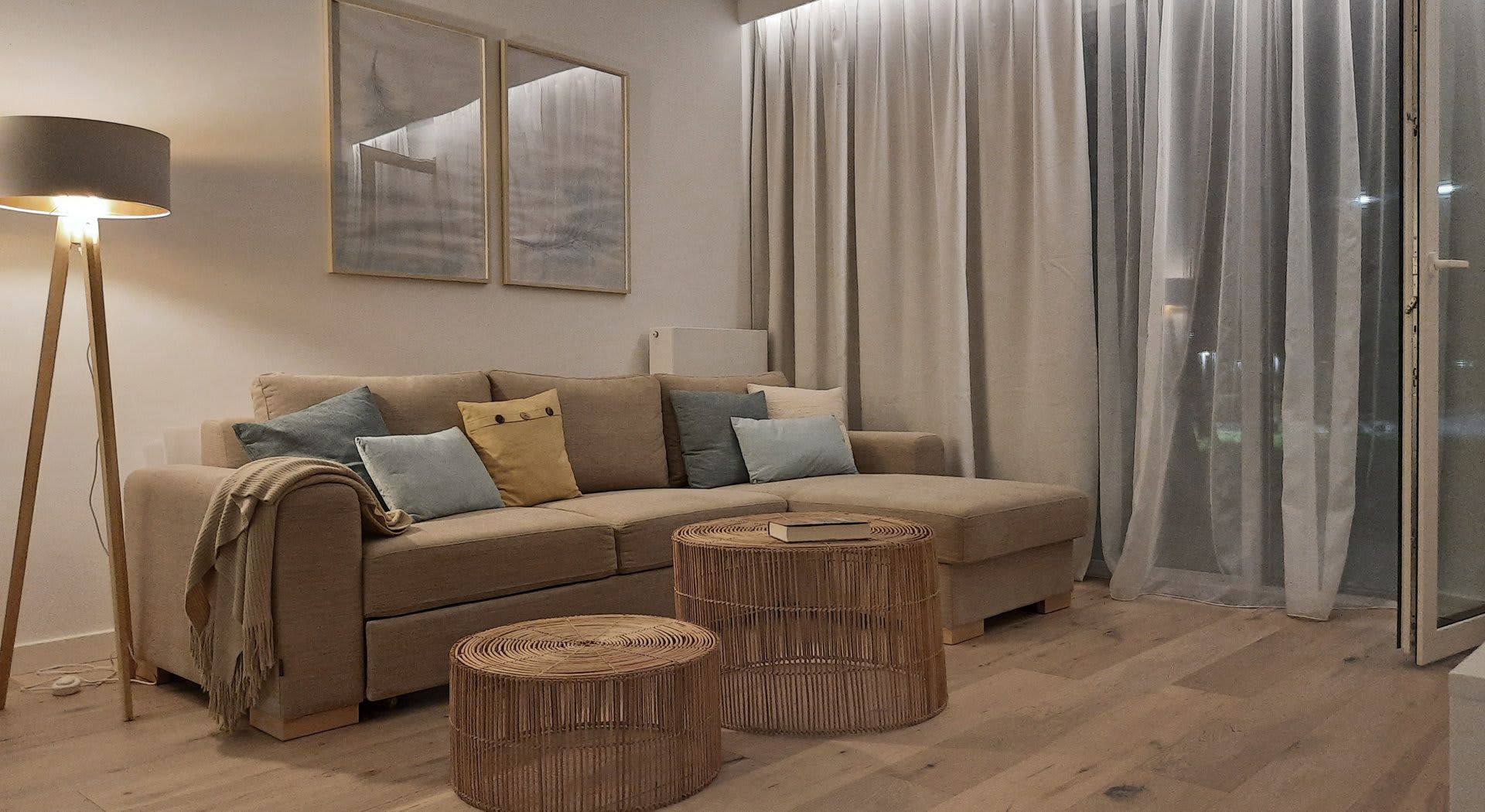 Przytulny salon z brązową sofą narożną, stolikami z pni drzew i lampą podłogową.