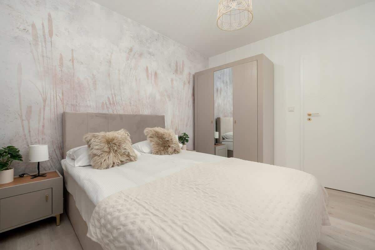 Sypialnia z łóżkiem, szafką nocną, szafą i wzorzystą ścianą dekoracyjną.