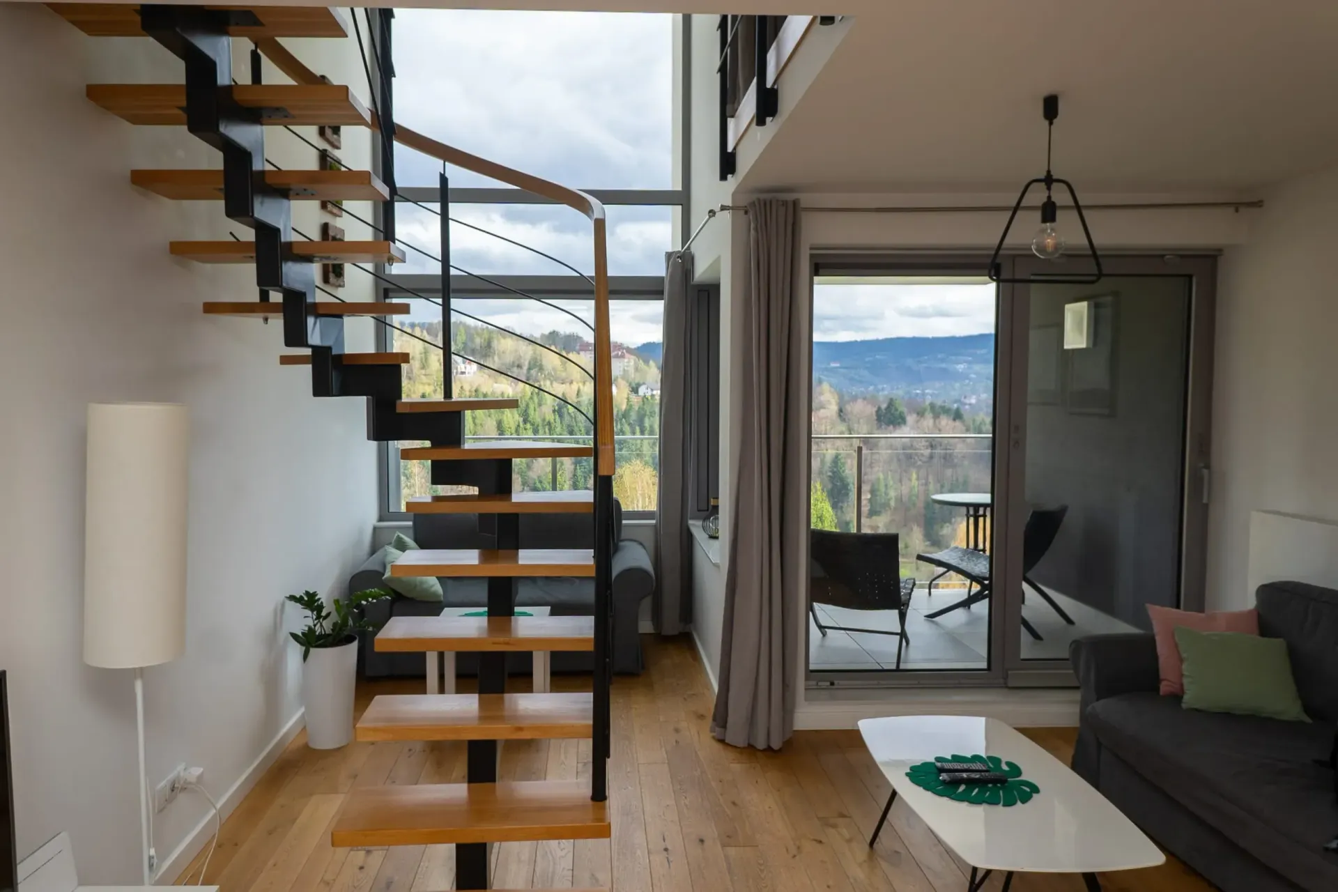 Nowoczesny apartament z drewnianymi schodami, balkonem z widokiem na góry i sofą.