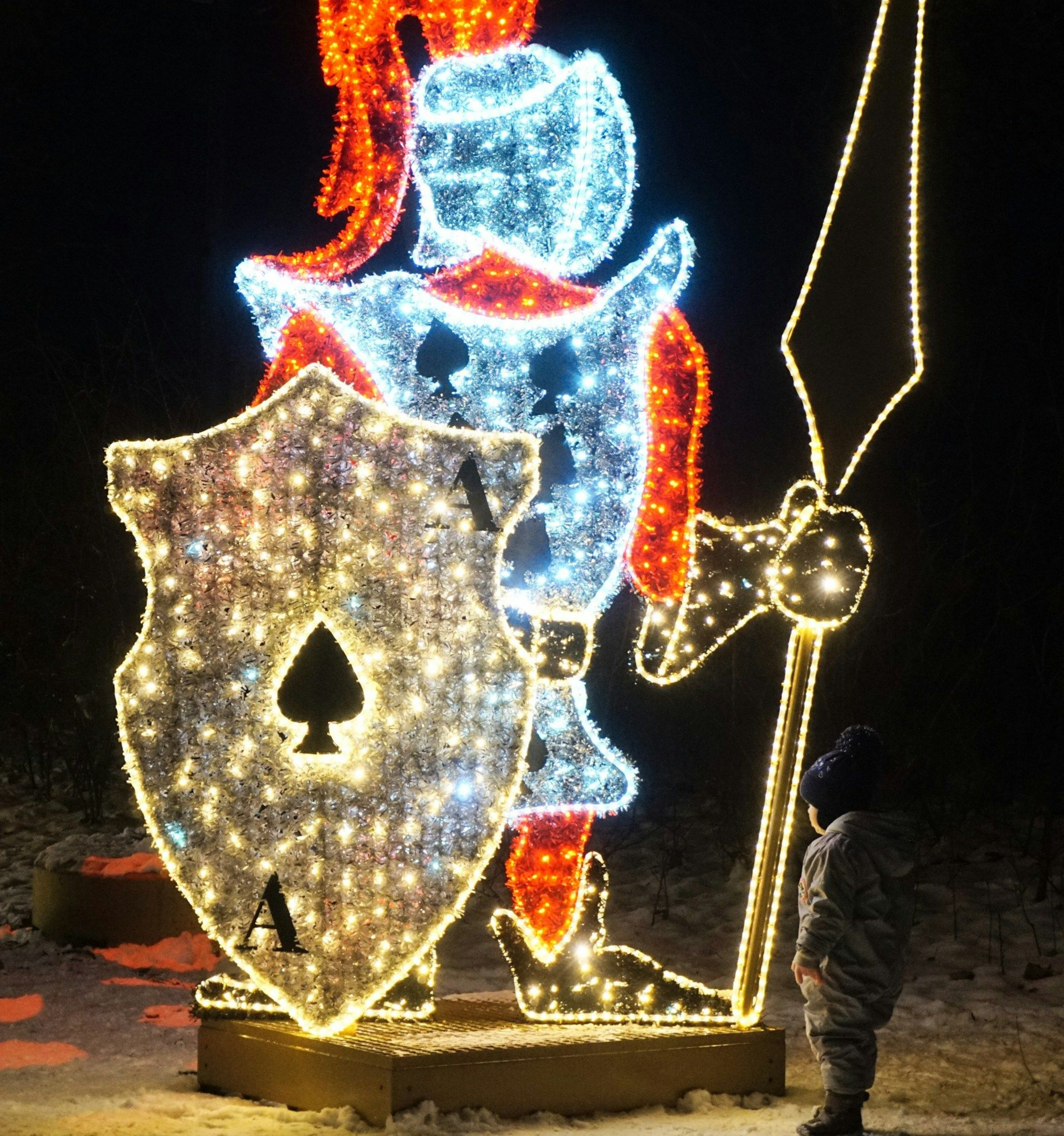 Świąteczna iluminacja: postać rycerza z tarczą w kształcie piki i dziecko patrzące w górę.