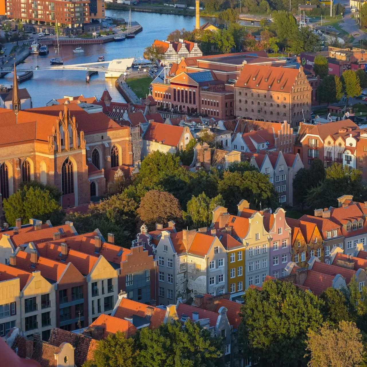 Panorama Gdańska, Polska, z pomarańczowymi dachami, budynkami, rzeką i łodziami.