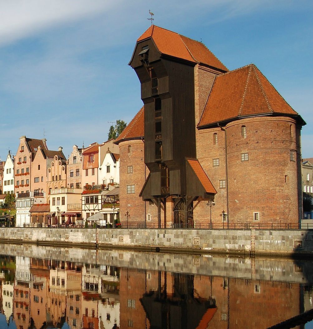 Duży ceglany budynek stoi obok zbiornika wodnego