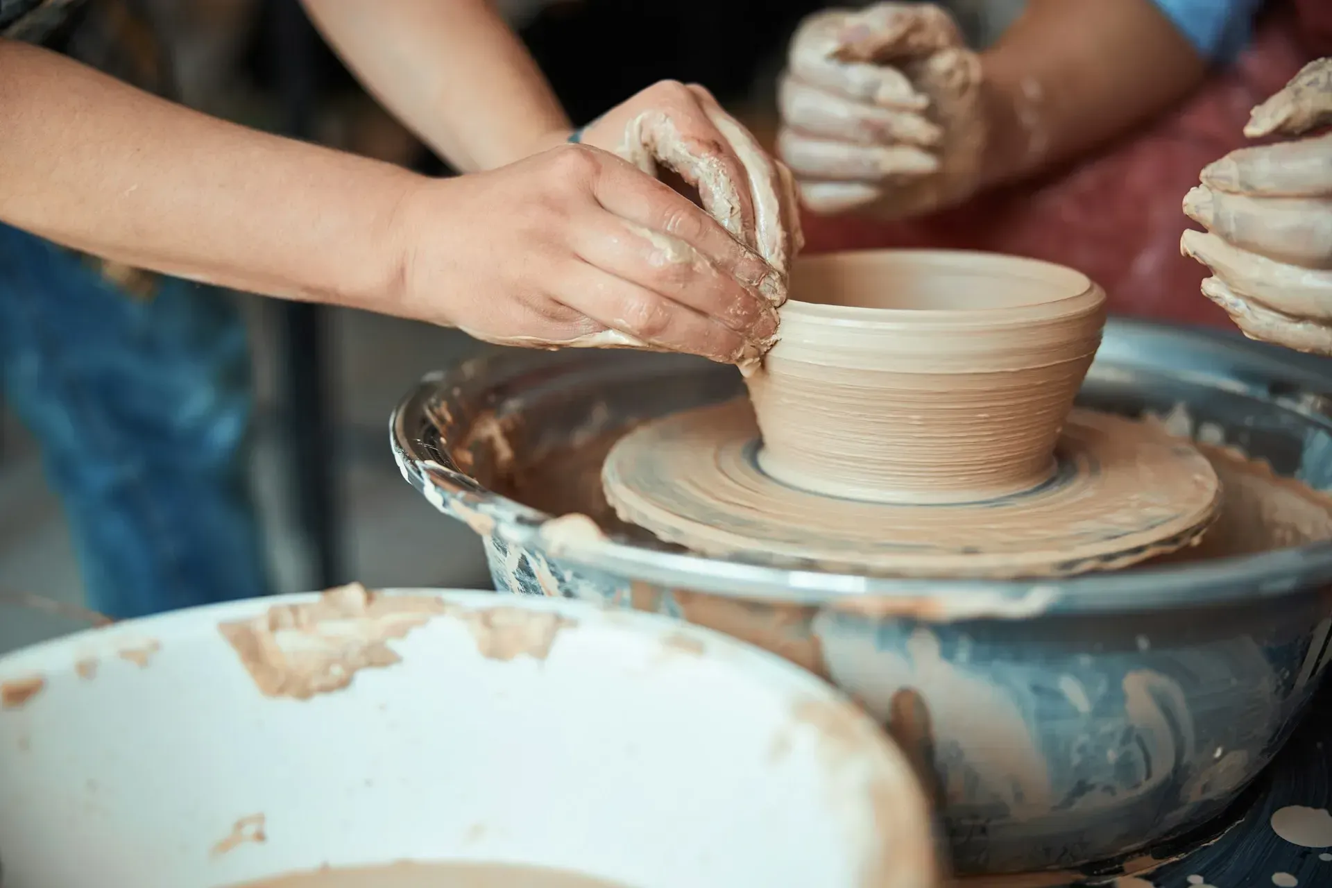 Hands shaping clay on a pottery wheel, a person learning ceramics.