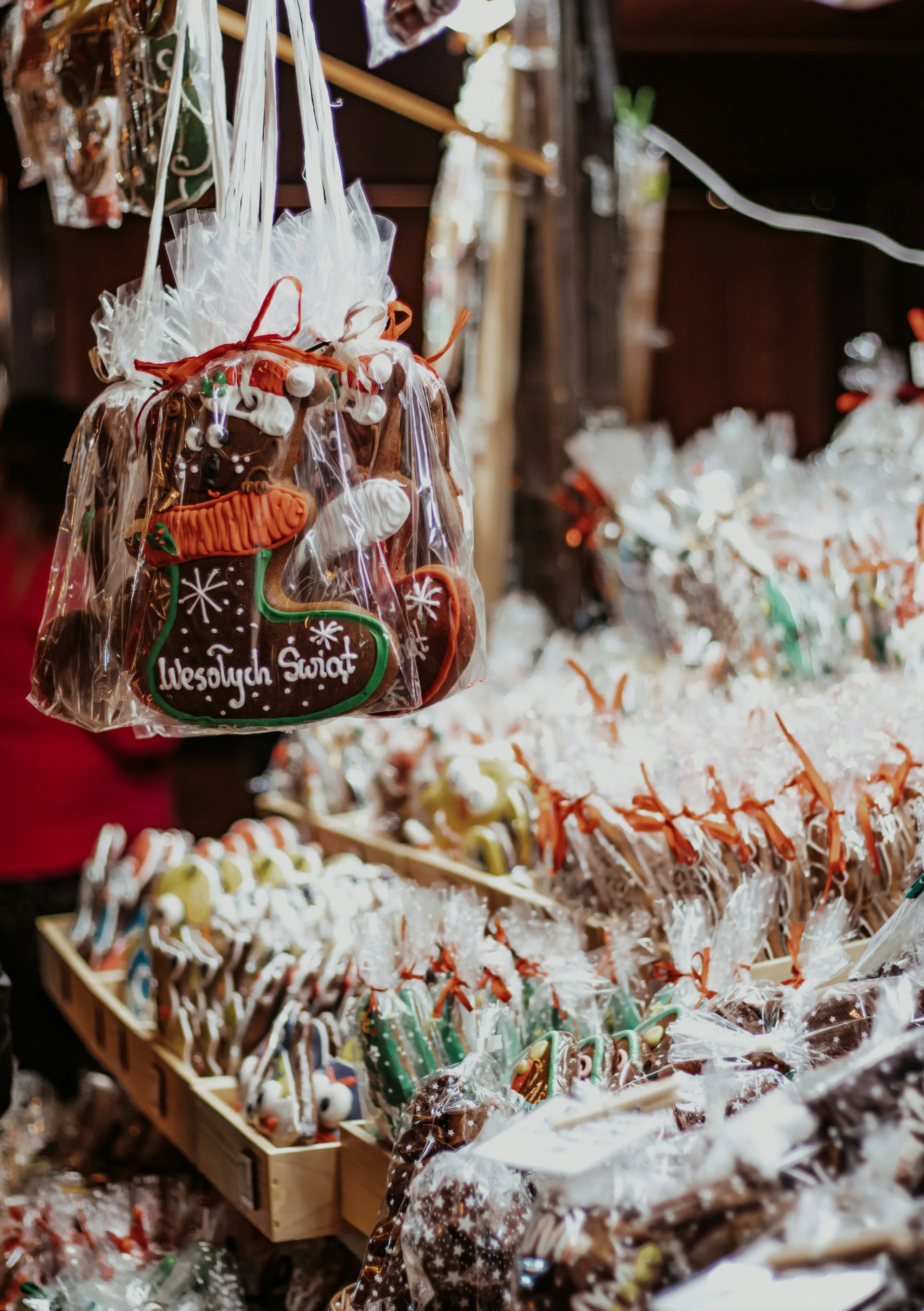 Wystawa pierniczków na jarmarku bożonarodzeniowym w plastikowych torebkach i tackach.