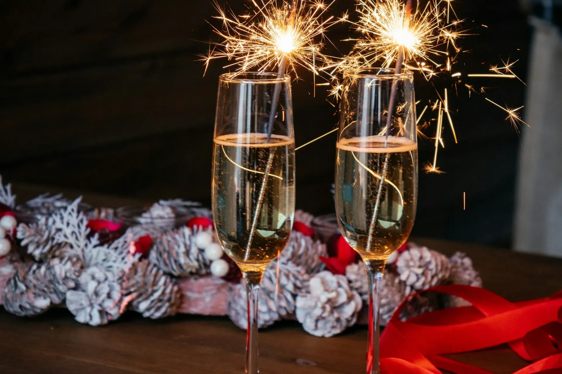 dwa kieliszki z szampanem i zimnymi ogniami, podczas świętowania nadejścia Nowego Roku