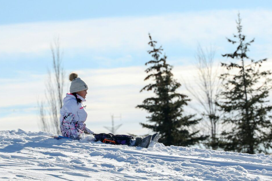 Osoba zjeżdża na sankach z pokrytego śniegiem wzgórza.