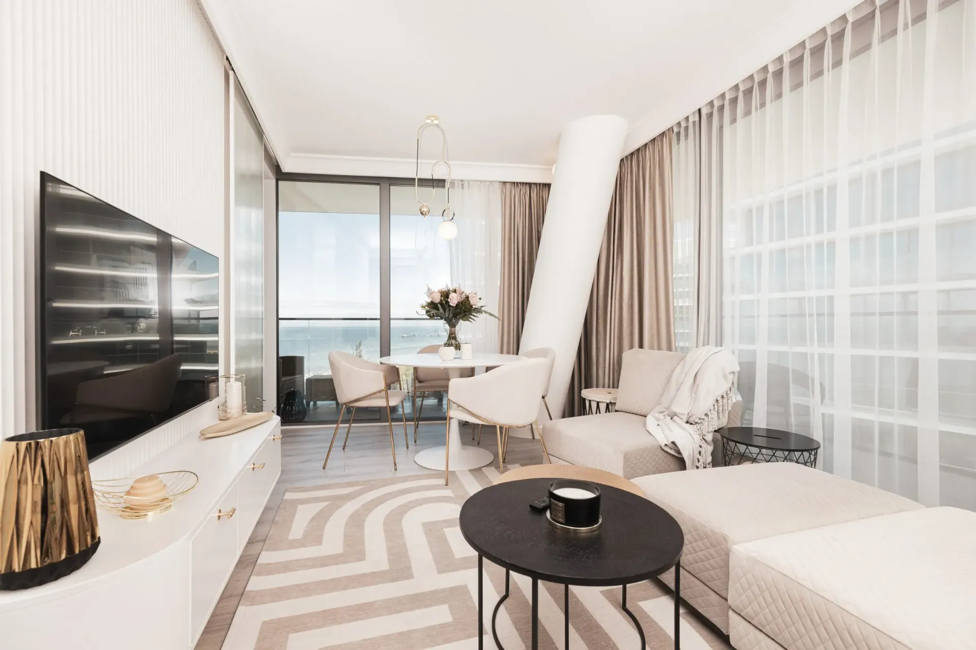 Nowoczesny salon w neutralnych kolorach, z widokiem na ocean i współczesnymi meblami.