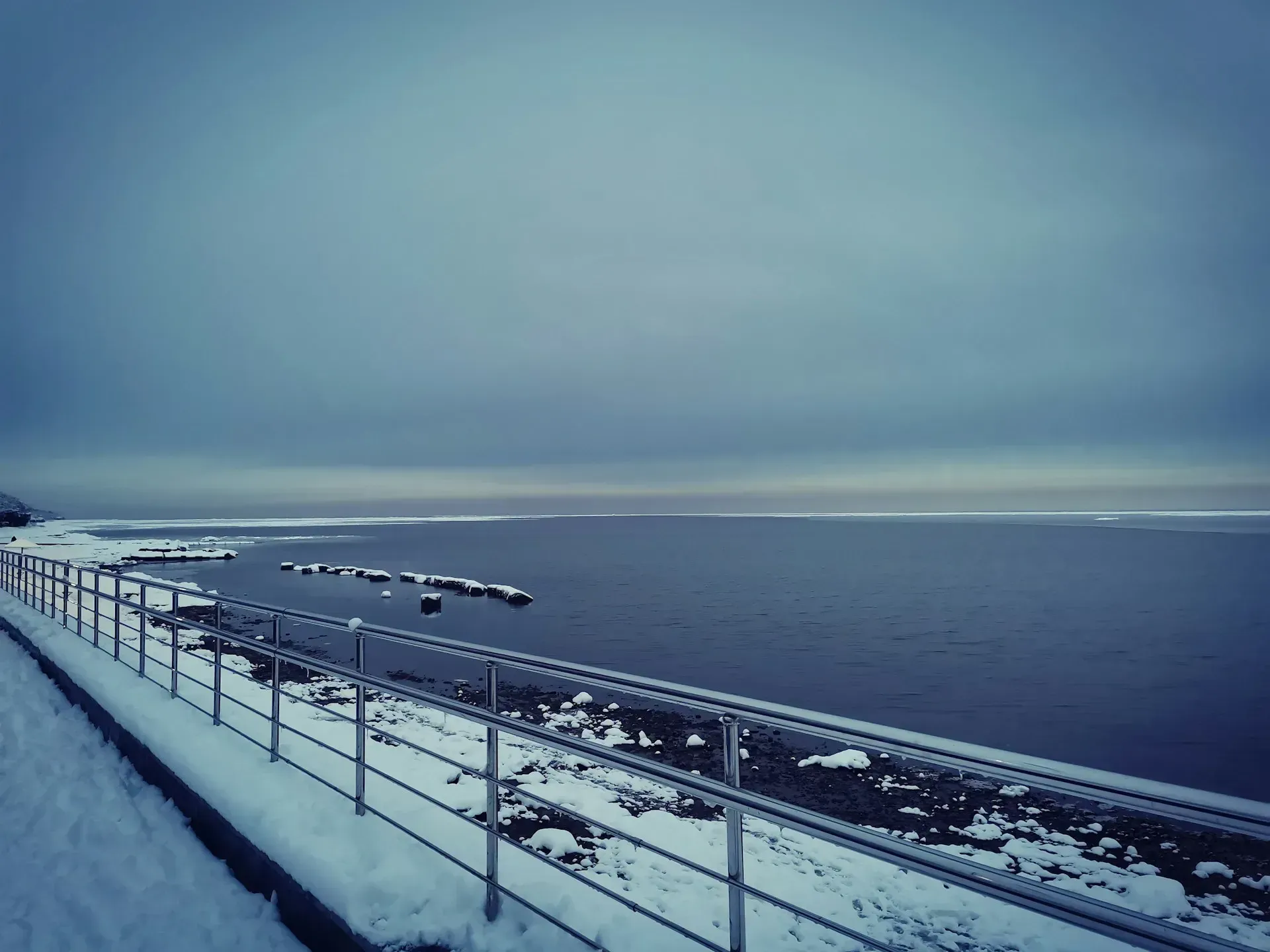 Widok na plażę, pokrytą śniegiem w mroźny zimowy dzień.