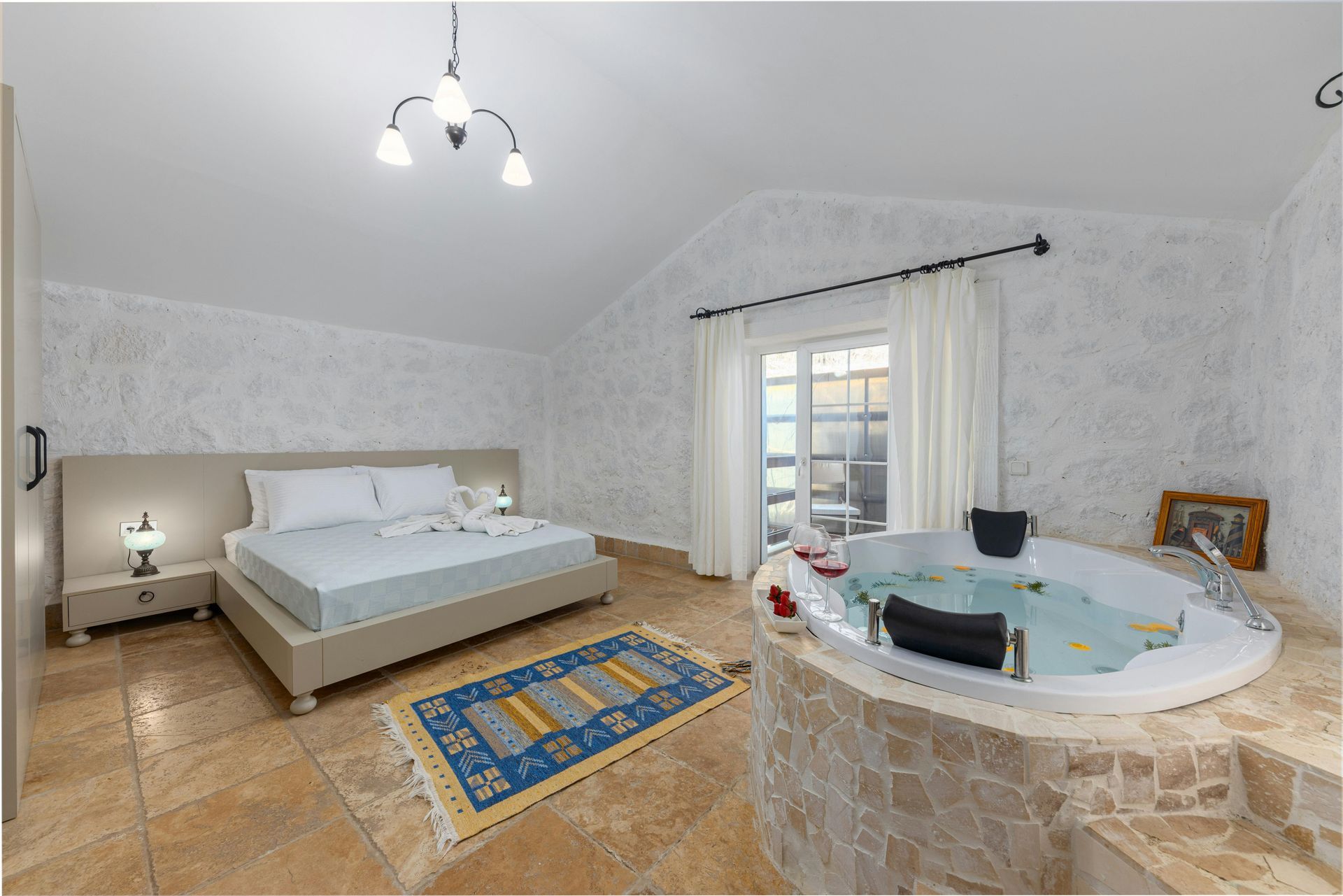 Sypialnia z łóżkiem, dywanem i wanną z hydromasażem. Białe, teksturowane ściany i kafelkowa podłoga.