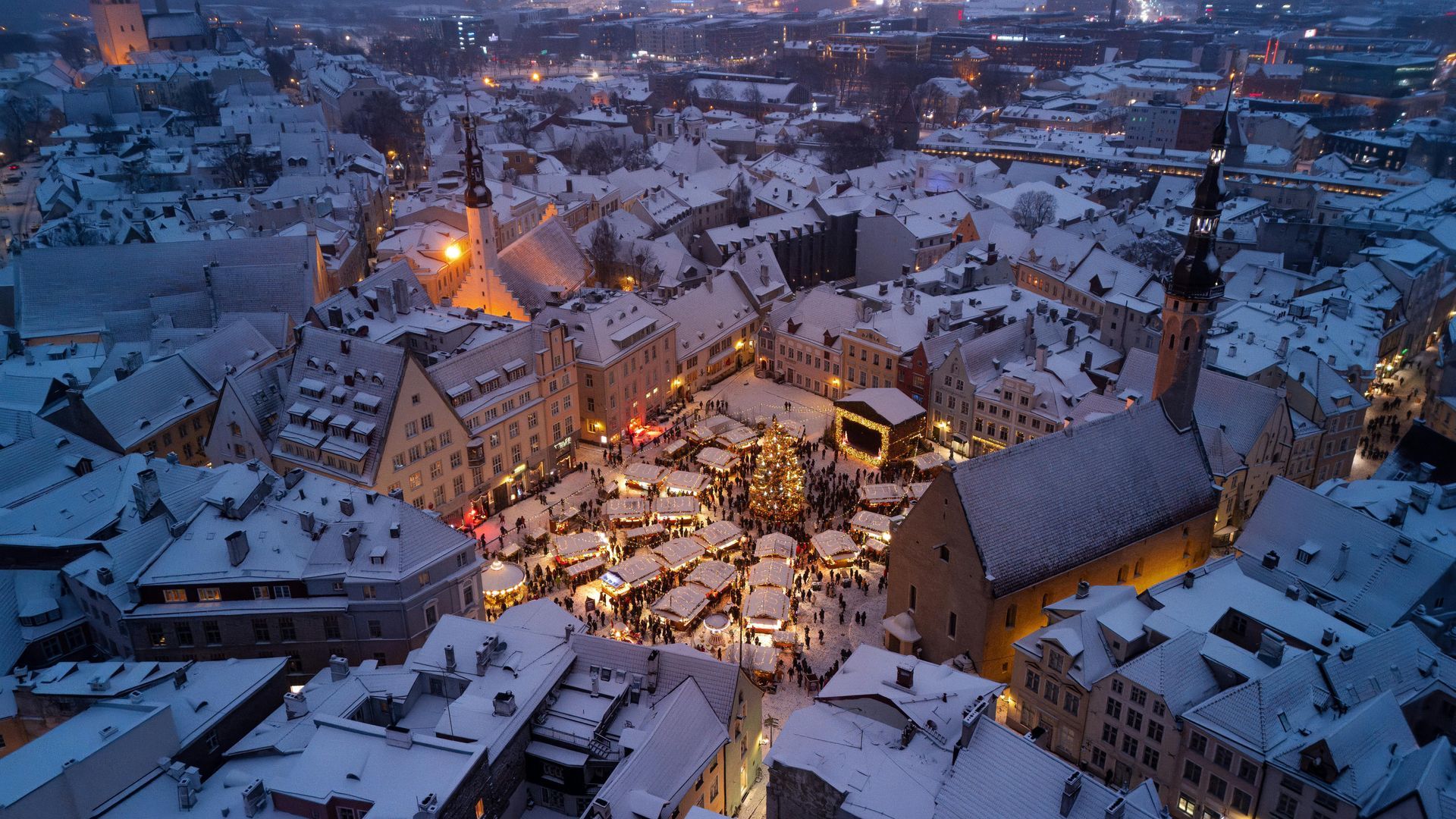 Aerial view of snowy, illuminated Old Town square, possibly during Christmas market.