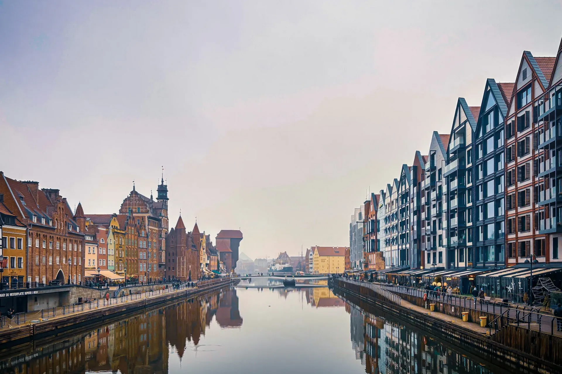 Canal with colorful buildings, Gdansk, Poland. Cloudy sky. People along the waterfront.
