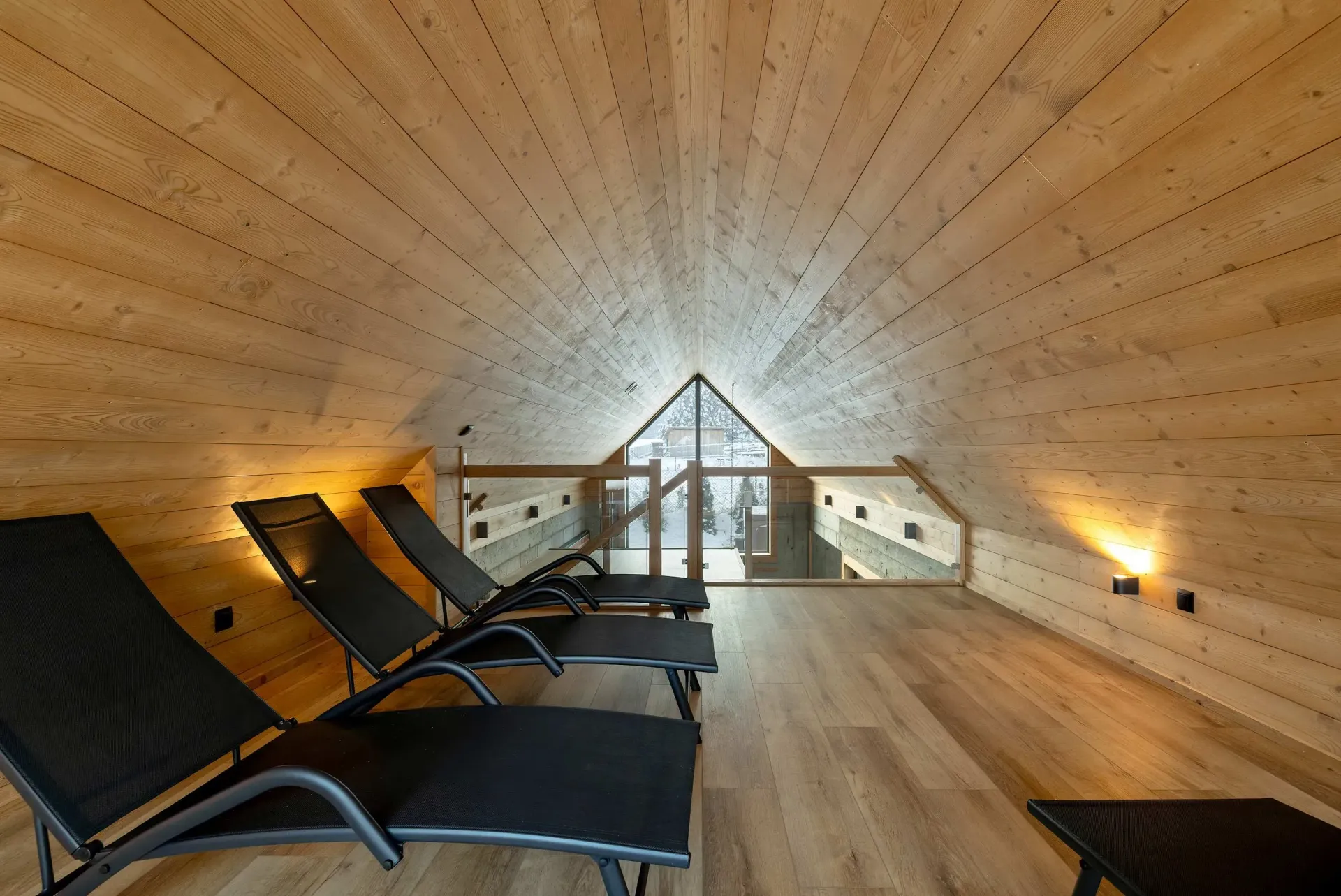 Drewniane wnętrze sauny z leżakami, oknem oraz drewnianą podłogą i sufitem.