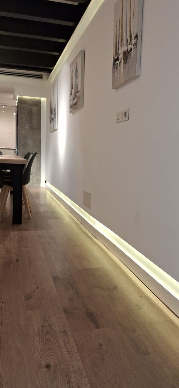 Interior de tienda moderno y minimalista con iluminación naranja, mostradores blancos y ventanas que dan a la calle.