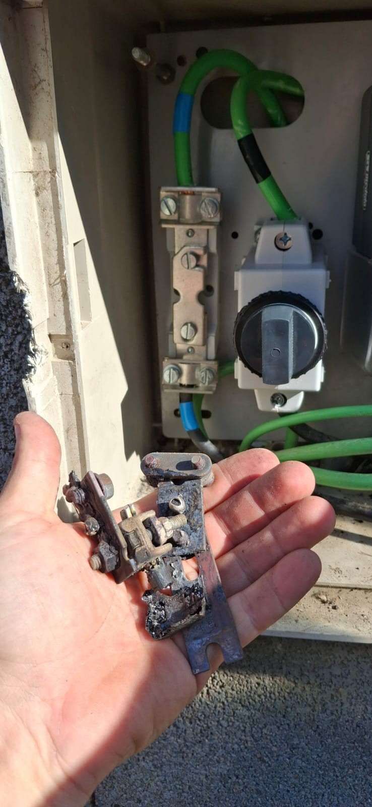 Tres interruptores automáticos eléctricos con palancas blancas y cables negros gruesos en una caja de distribución.