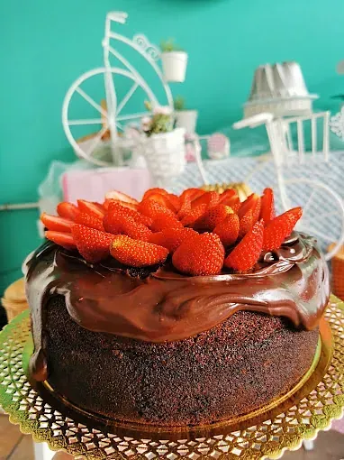 En un plato hay un pastel de chocolate con fresas encima.