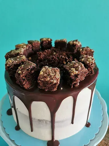 Un pastel con glaseado de chocolate y brownies encima.