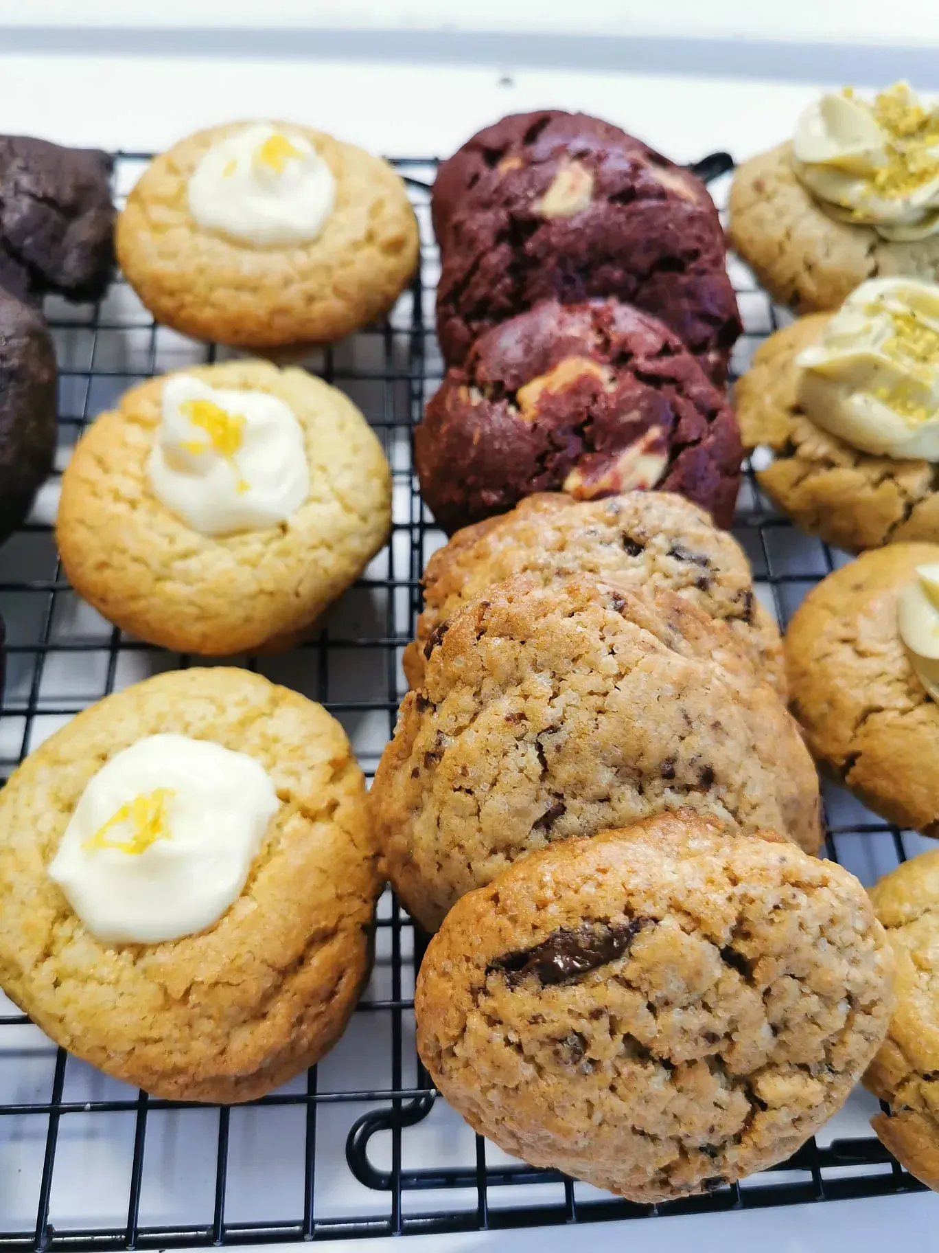 Una variedad de galletas se encuentran en una rejilla para enfriarse.