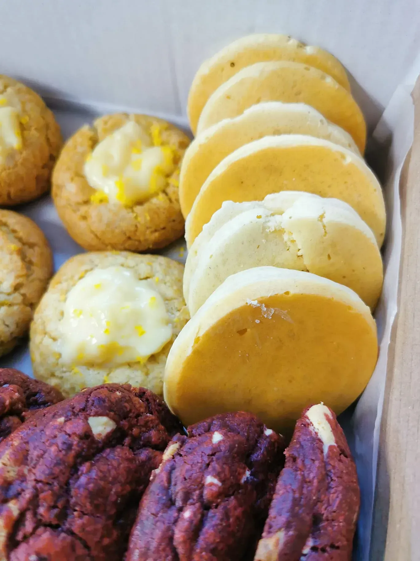 Una caja llena de una variedad de galletas, incluidas galletas de terciopelo rojo.