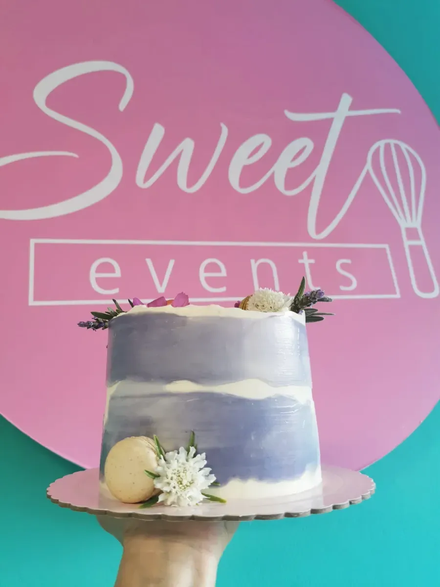 Una persona sostiene un pastel frente a un cartel que dice