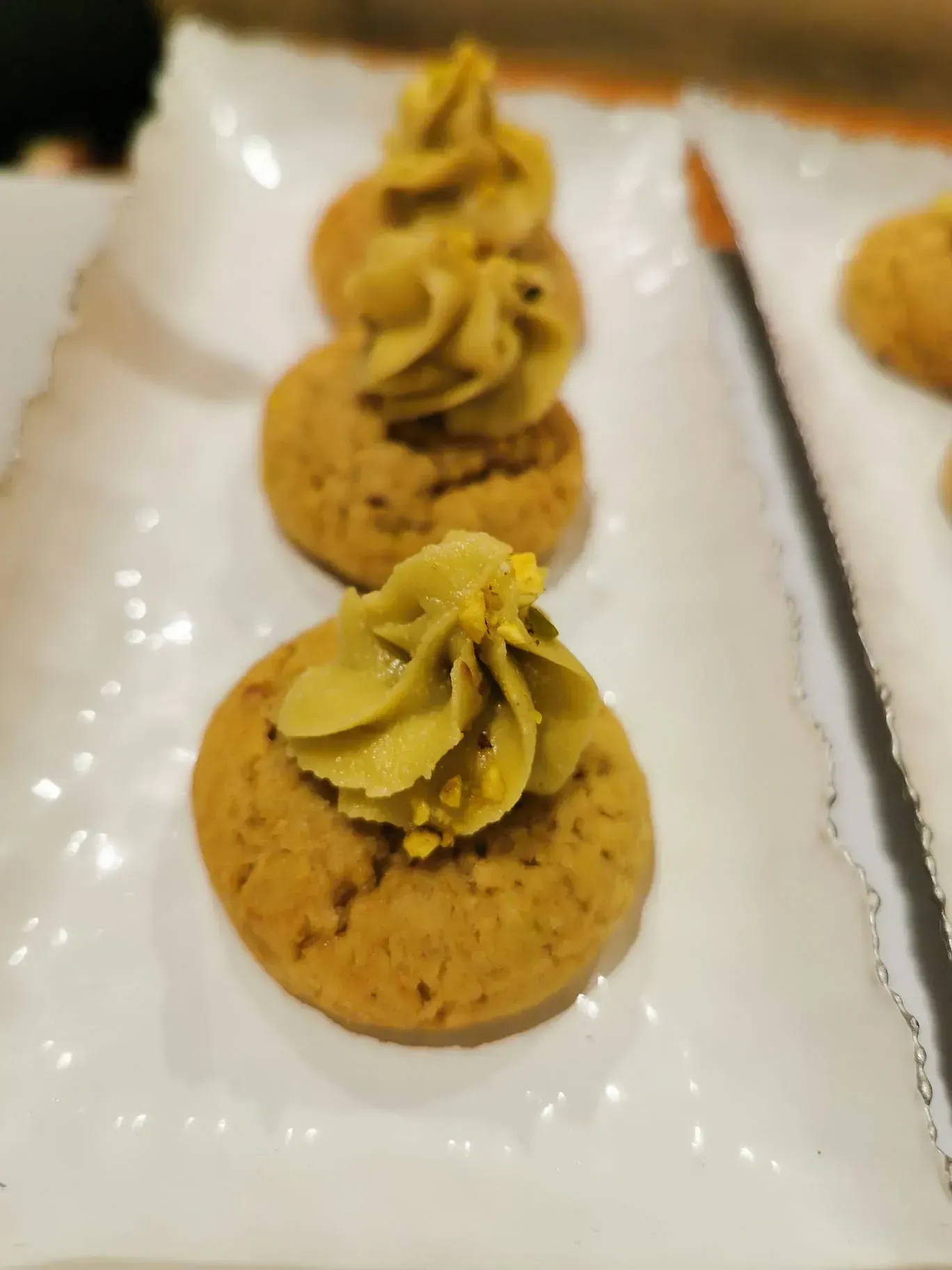 Un plato blanco cubierto con tres galletas con glaseado verde encima.