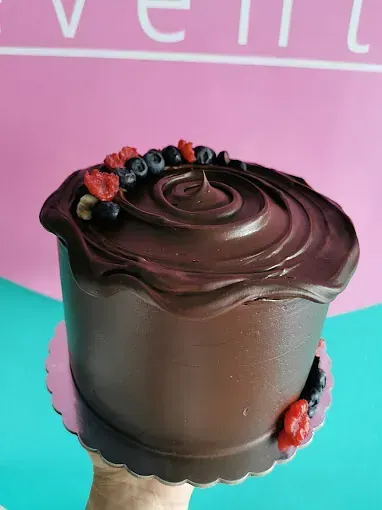 Una persona sostiene un pastel de chocolate con bayas encima.