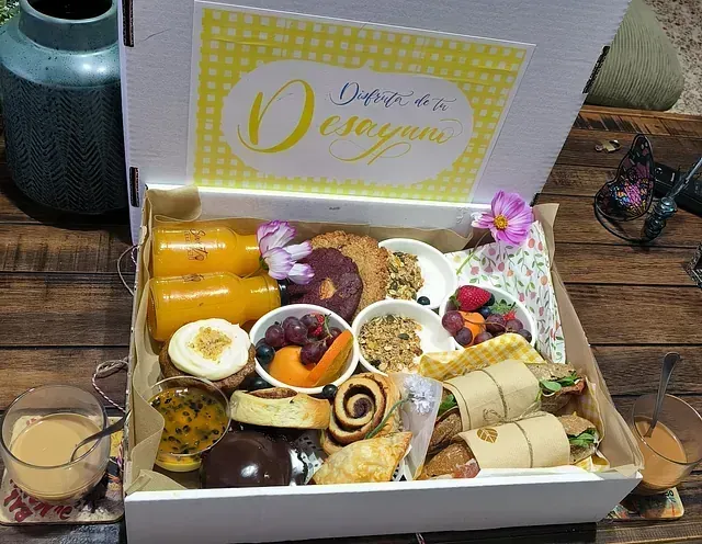 Una caja llena de una variedad de alimentos y bebidas sobre una mesa de madera.