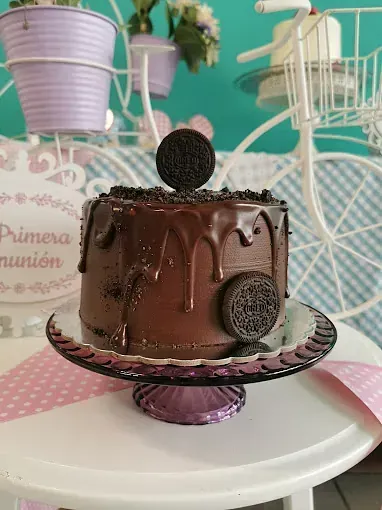 Un pastel de chocolate con galletas Oreo encima está sobre un plato de vidrio sobre una mesa.