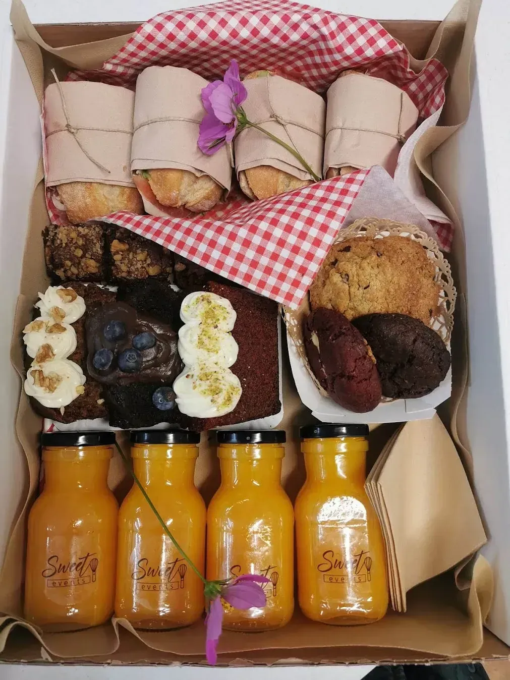 Una caja llena de una variedad de postres y jugos.