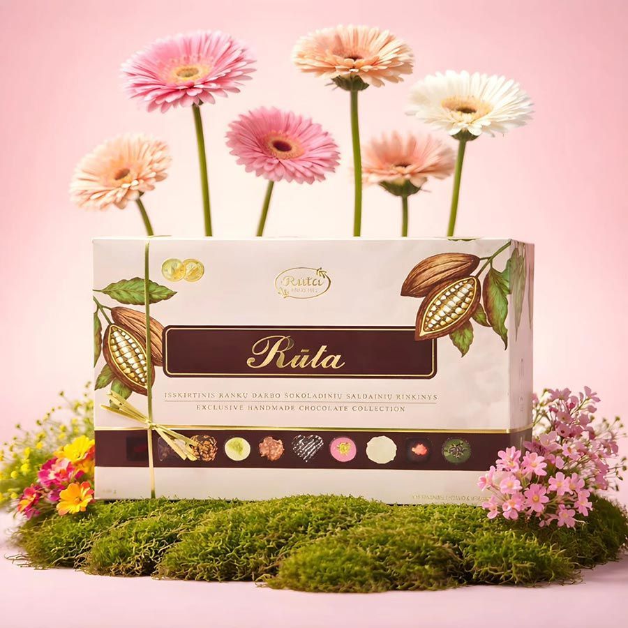 Elegante caja de regalo color crema con detalles florales y gerberas rosas sobre una base de musgo, con un fondo rosa