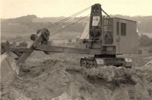 Ein Schwarzweißfoto eines Bulldozers, der Erde auf einem Feld bewegt.