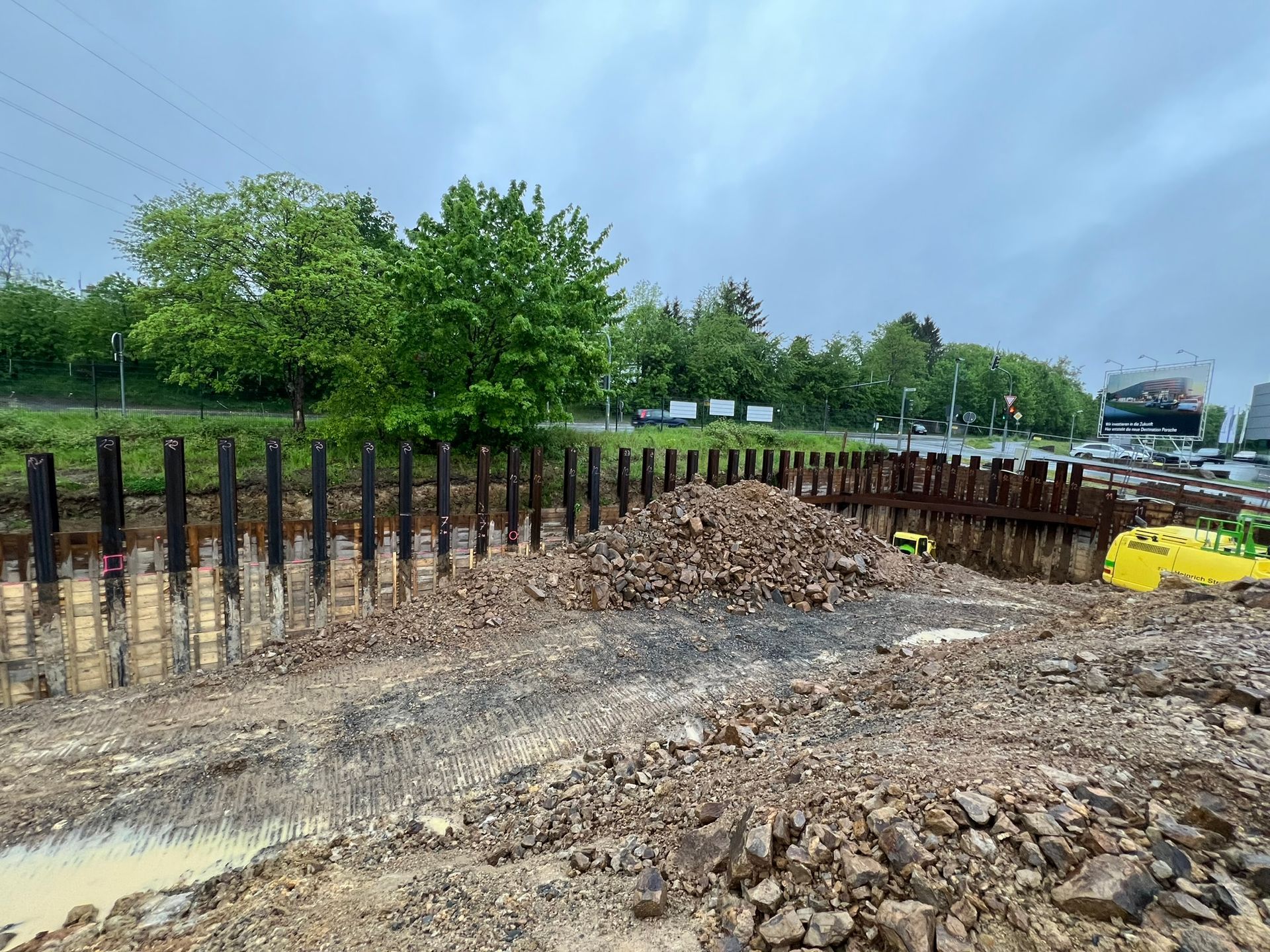 Eine Baustelle mit einem Erdhaufen und Bäumen im Hintergrund.