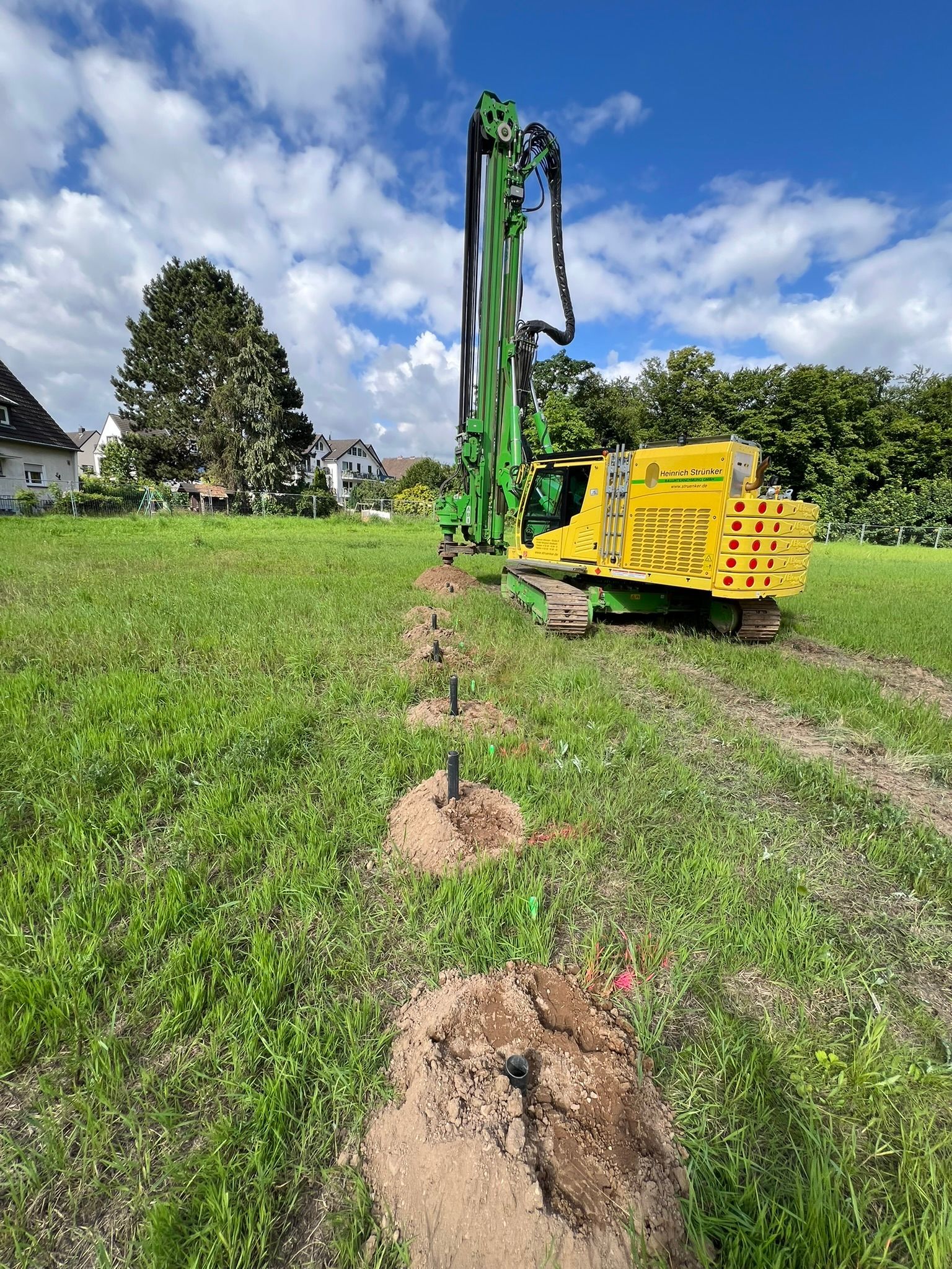 Ein gelb-grünes Baufahrzeug fährt durch eine Wiese.