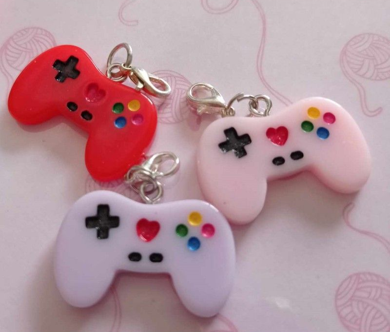 Trois porte-clés colorés pour manette de jeu avec fermoirs argentés. Rouge, rose et lavande, avec boutons en forme de cœur/croix.