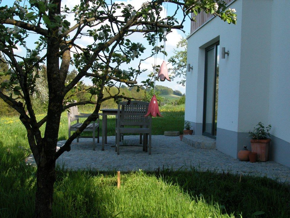 Ein weißes Haus mit einer Terrasse und einem Baum davor. Foto von Eder Christiane Kosmetikstudio
