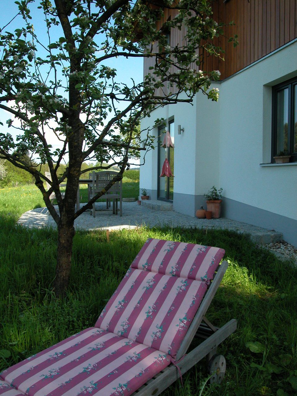 Ein rosa-weiß gestreifter Gartenstuhl steht im Gras. Foto von Eder Christiane Kosmetikstudio