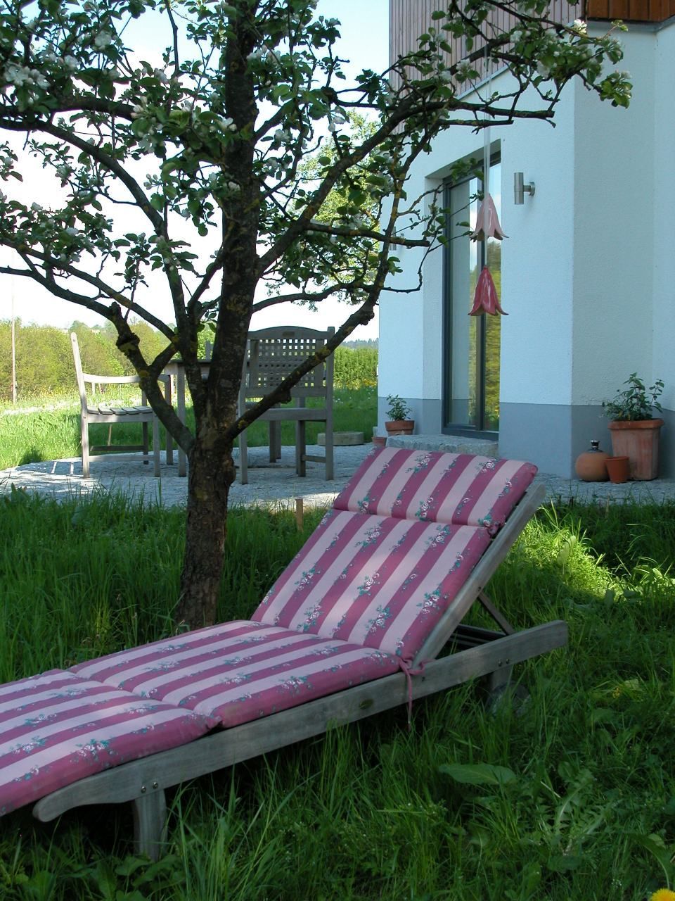 Ein rosa-weiß gestreifter Gartenstuhl steht im Gras. Foto von Eder Christiane Kosmetikstudio