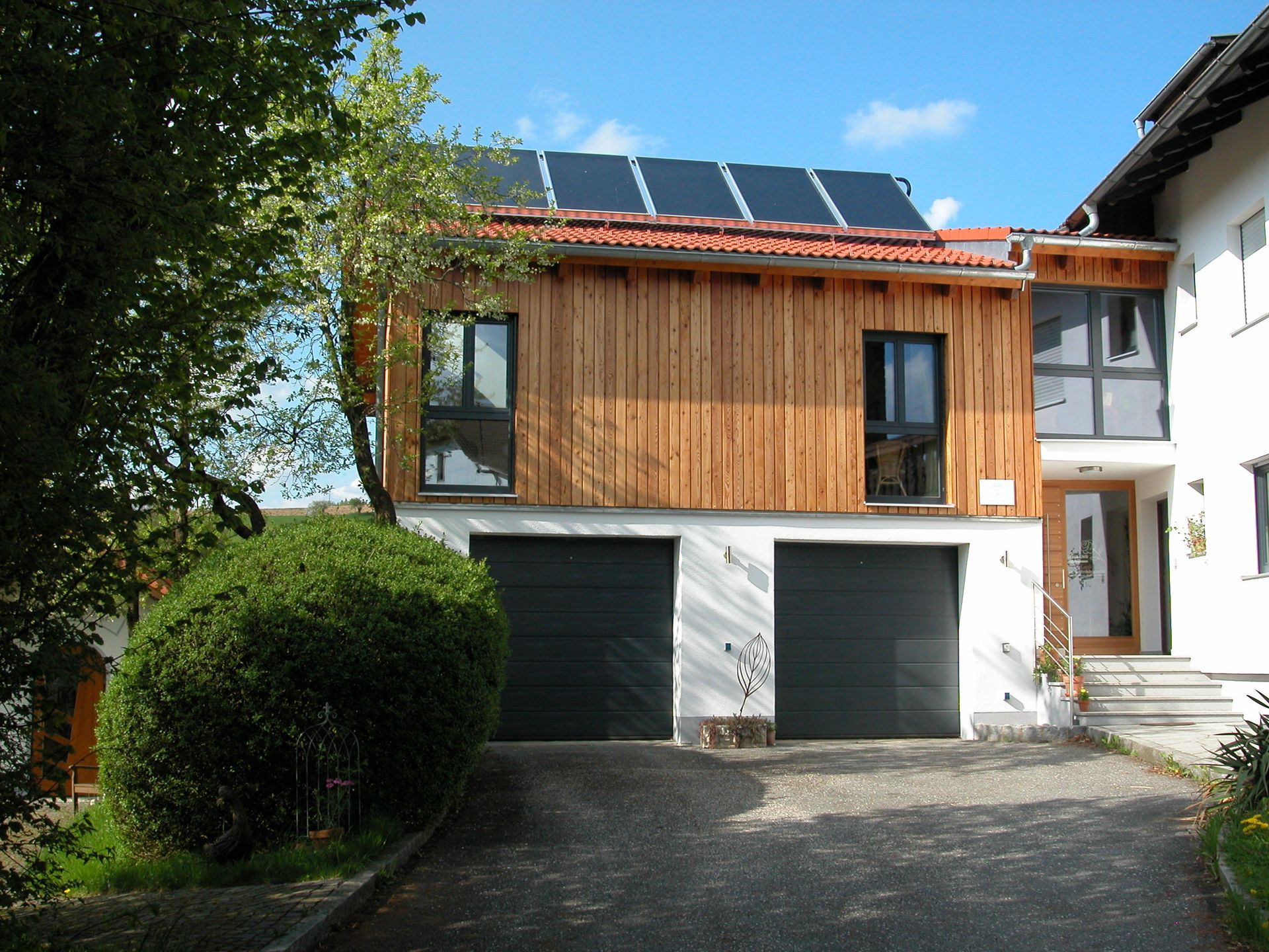 Ein Haus mit zwei Garagentoren und Sonnenkollektoren auf dem Dach. Foto von Eder Christiane Kosmetikstudio