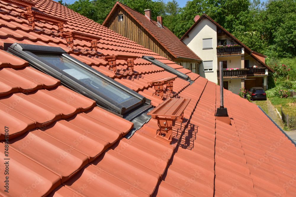 Ein rotes Ziegeldach mit zwei Oberlichtern darauf