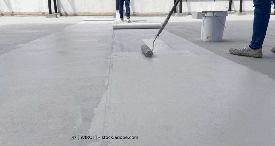 Eine Person streicht einen Betonboden mit einer Rolle.