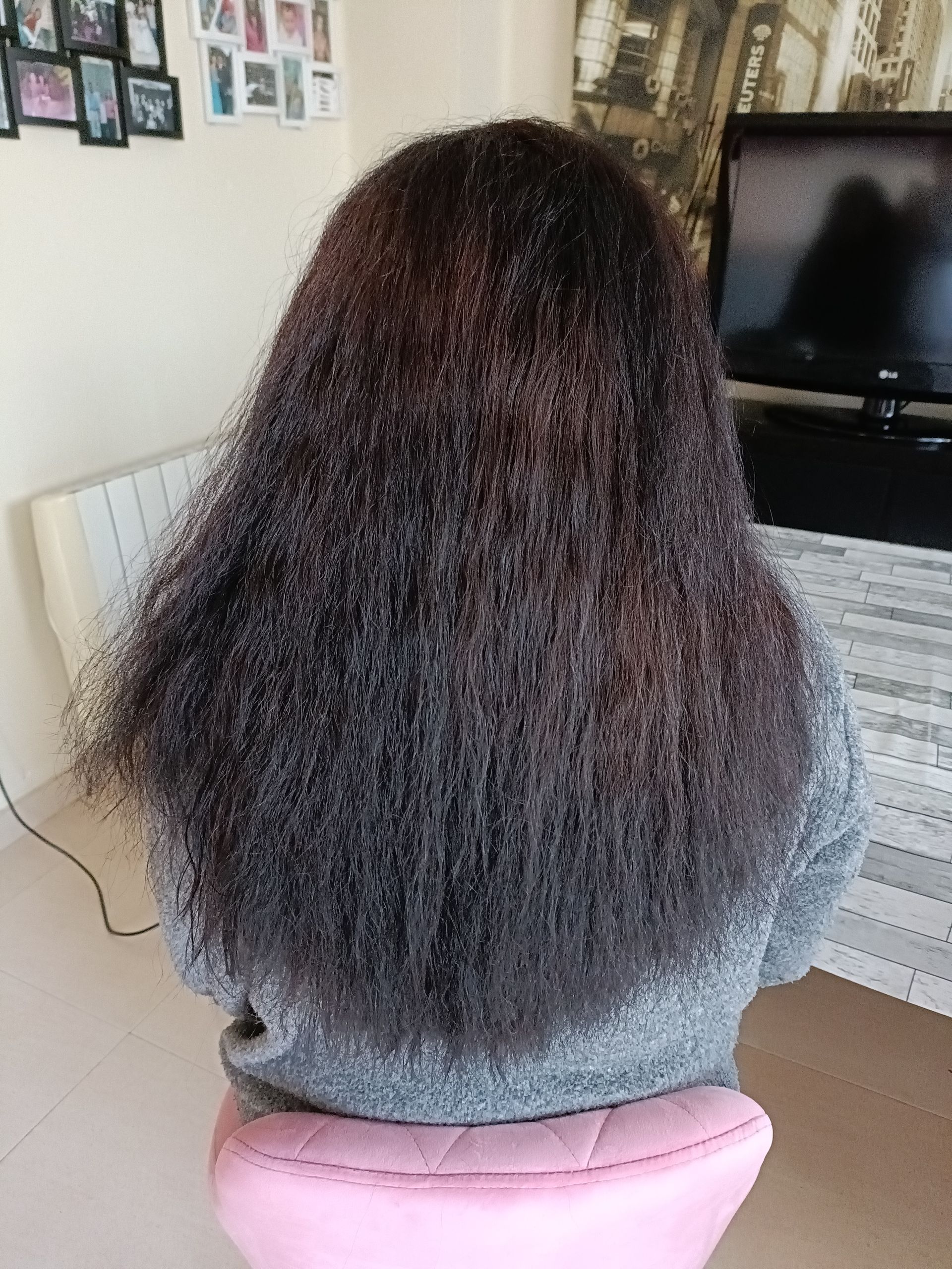 Una peluquera está peinando a una mujer en un salón de belleza. Al fondo se ven otros clientes, espejos