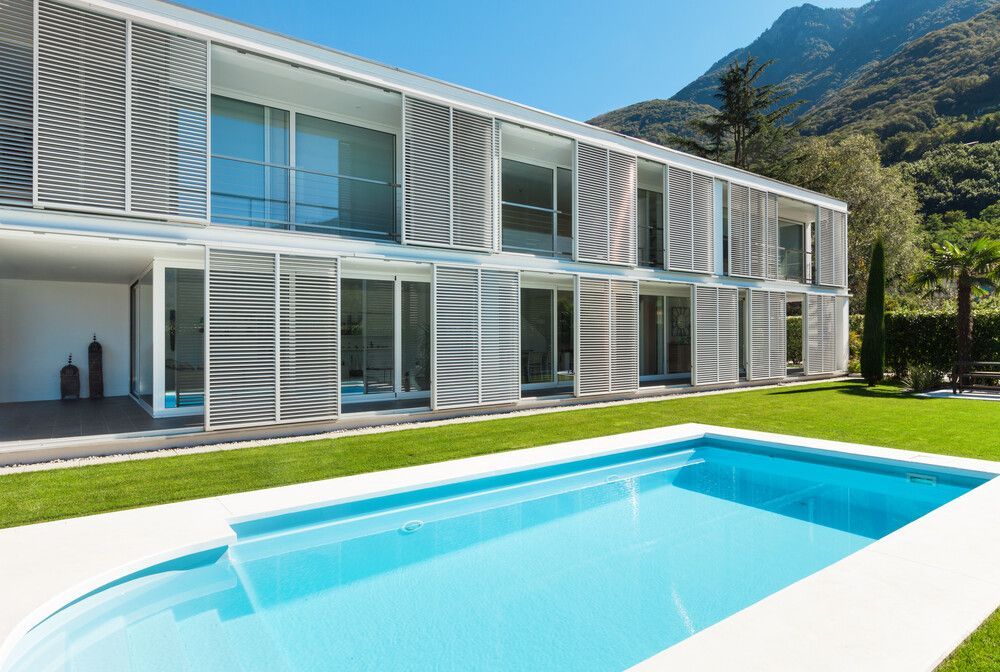 Una casa grande con piscina delante de ella.